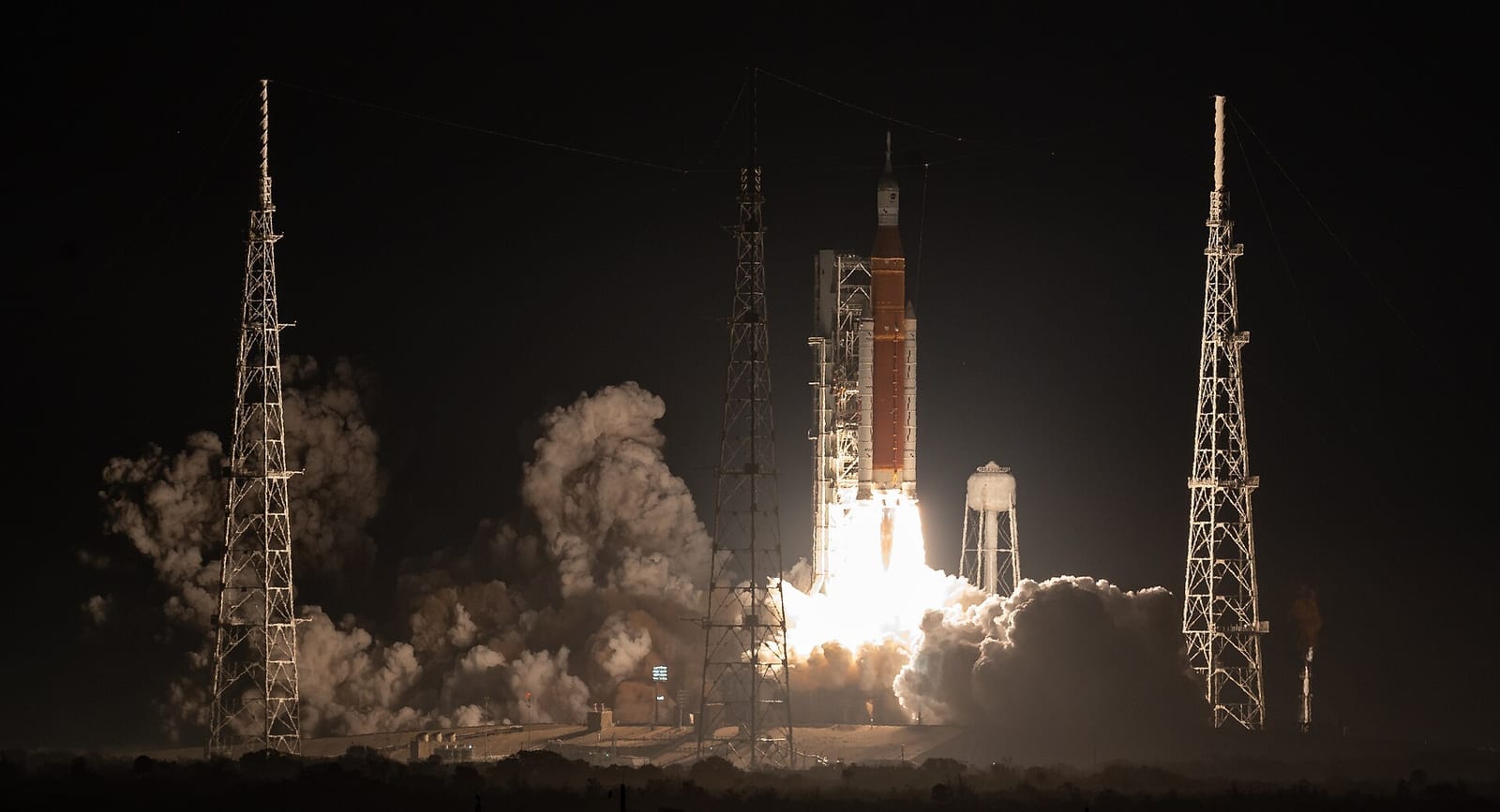 The Space Launch System rocket with the Orion spacecraft lifting off at night