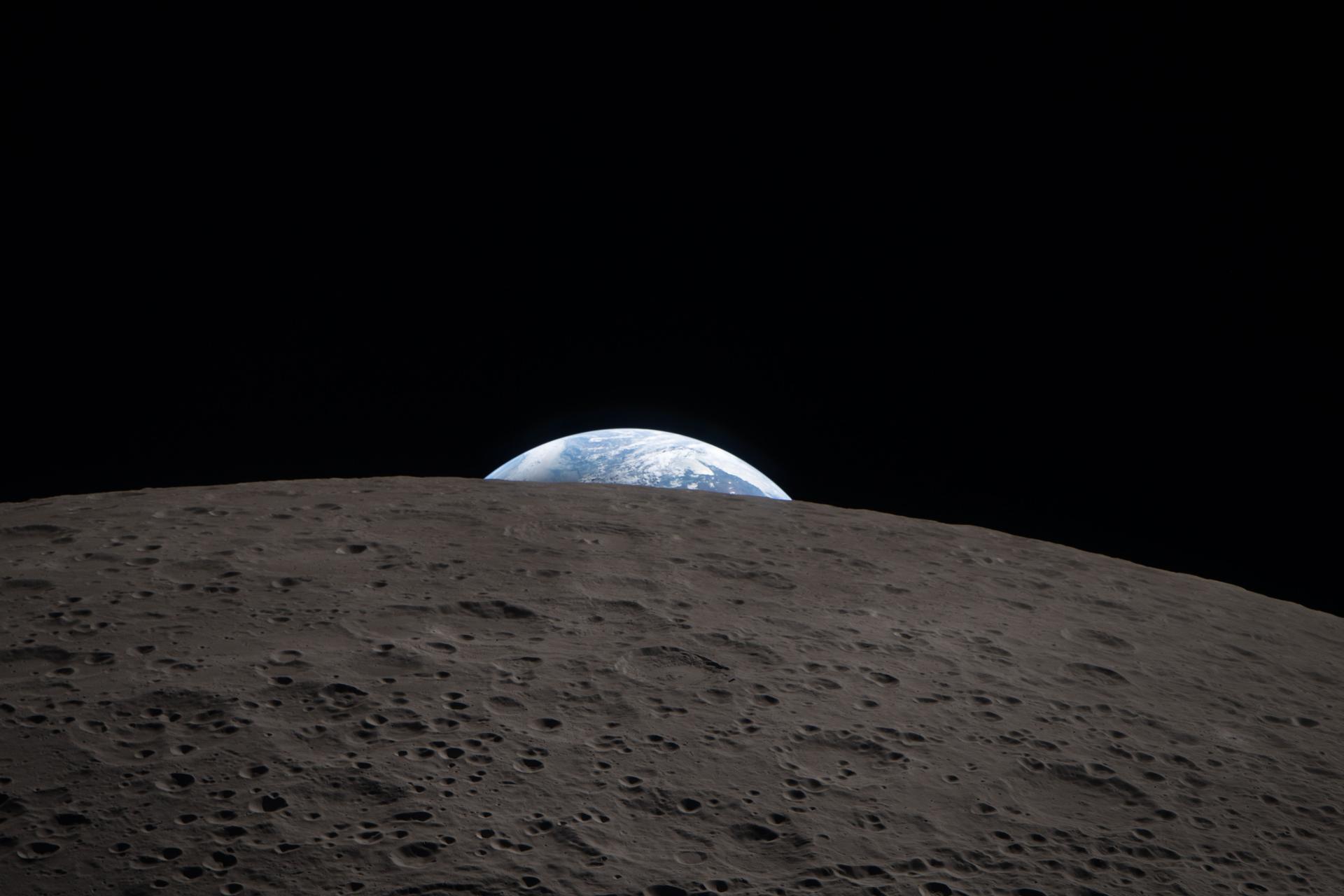 Earth setting behind the cratered limb of the Moon, seen from NASA’s Orion spacecraft