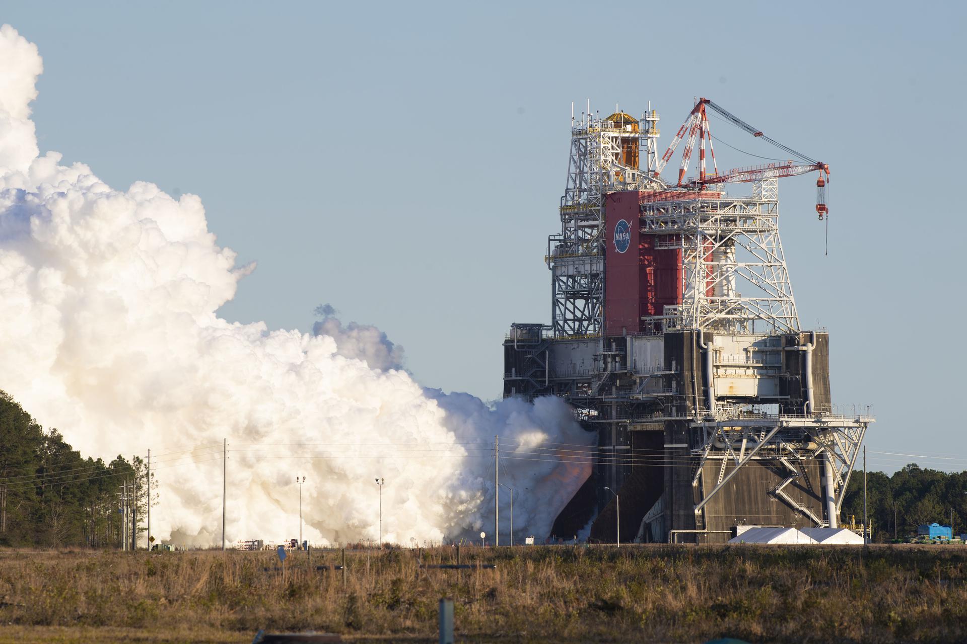 A rocket engine hot-fire test on a NASA test stand, throwing off a huge cloud of steam
